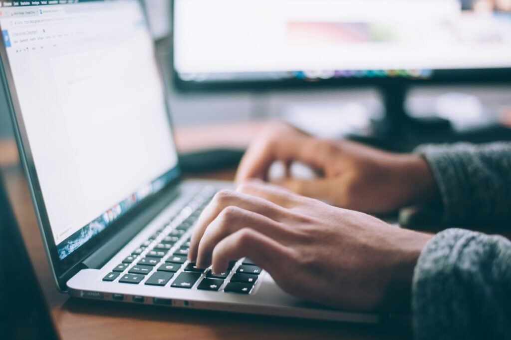 Person using a laptop to write and improve a resume with AI, illustrating the use of AI tools to create a professional, ATS-friendly resume for job applications.