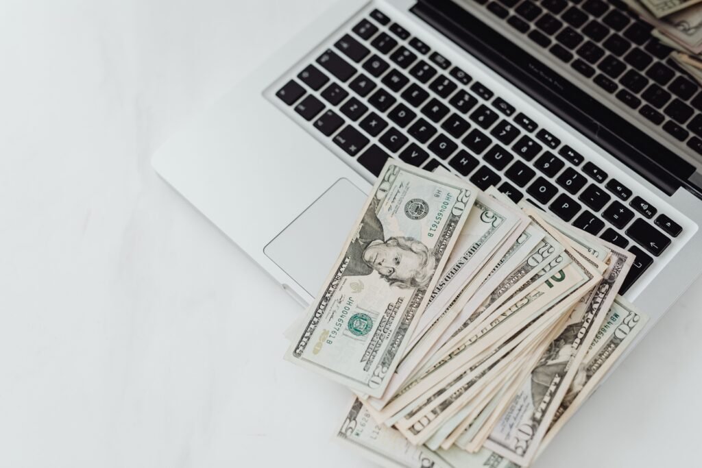 Banknotes placed on a laptop keyboard, representing the cost and value of investing in a Midjourney subscription for high-quality AI image generation.
