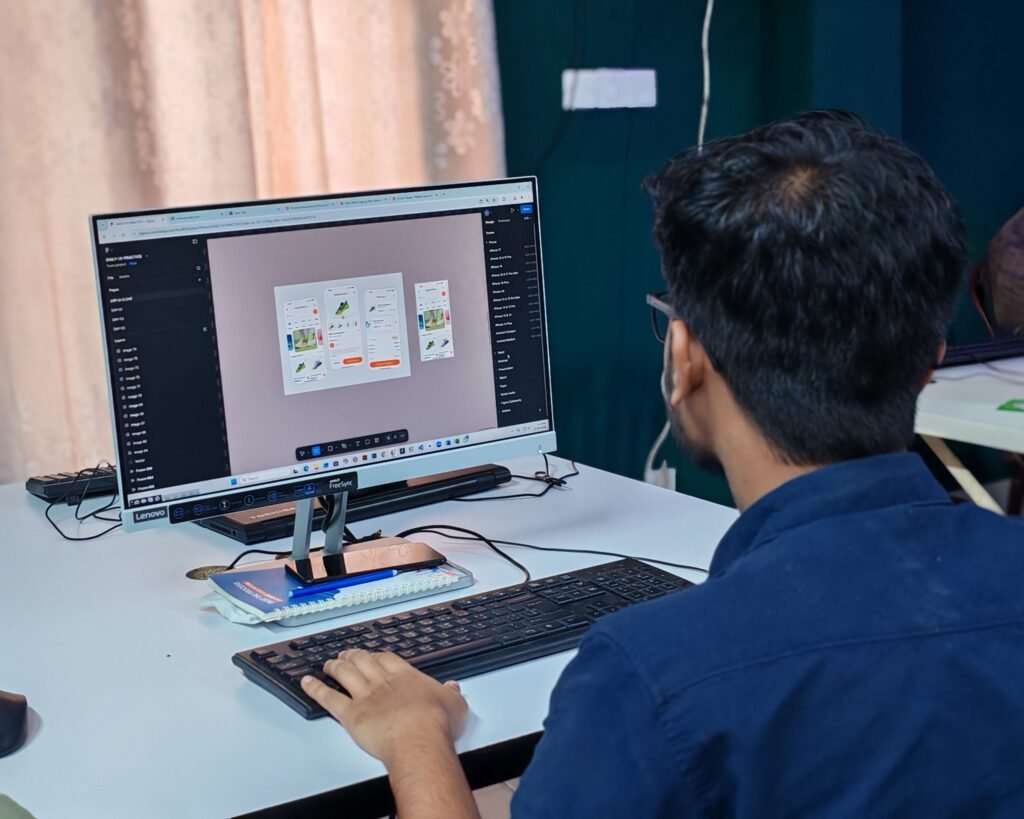 Young designer creating a user interface on a desktop computer in a modern workspace, showcasing UI/UX design, digital product development, and creative technology.