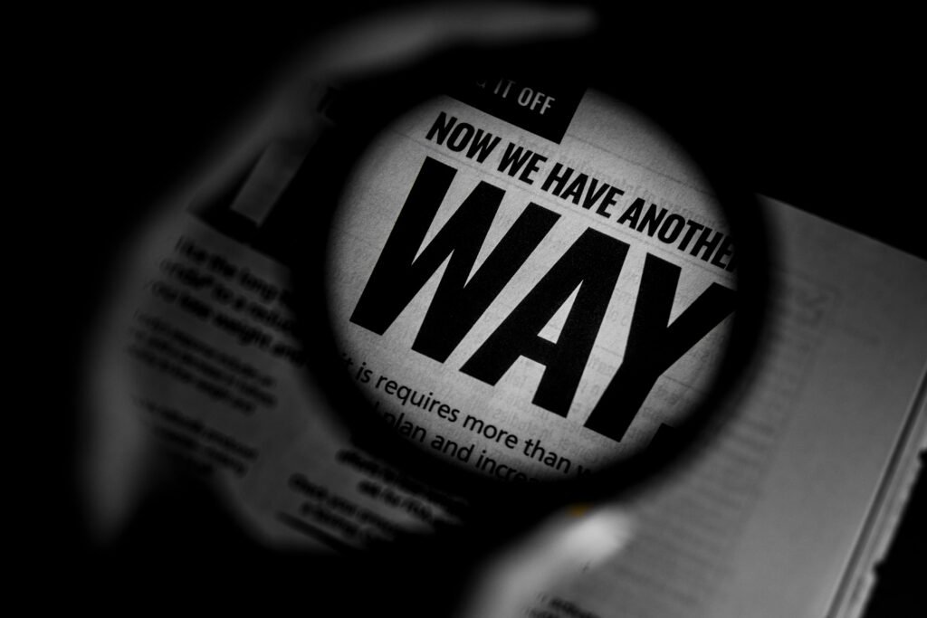 Magnifying glass over a newspaper headline, symbolizing comparing AI assistants and researching alternatives to find the best AI tool for different needs and use cases.