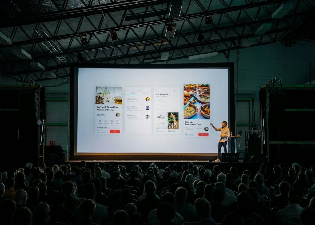 Presenter explaining AI-generated presentation slides on a large screen during a meeting, illustrating how AI helps create clear, professional, and engaging slide decks.